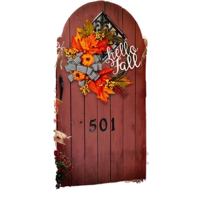 Autumn wreath with pumpkins and hello fall sign on a rustic wooden door with bow