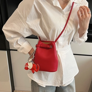 Nahaufnahme der roten Eimer-Tasche mit Lychee-Leder-Textur und Elefantenanhänger