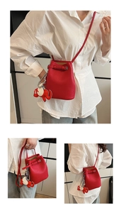 Details der roten Eimer-Tasche aus Leder mit Kieselmaserung und süßem Elefantenanhänger