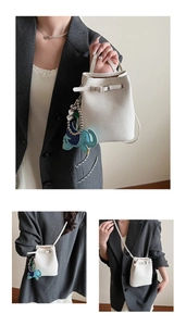 Drei Ansichten einer weißen Mini-Eimertasche aus Leder mit einem Elefanten-Anhänger