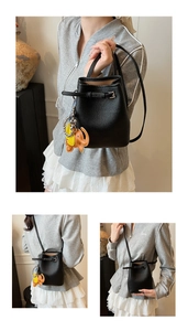 Detail der schwarzen Beuteltasche aus Leder mit orangefarbenem Elefantenanhänger und Gurt