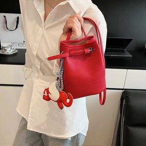 Detail der roten Beuteltasche aus genarbtem Leder mit Elefantenanhänger und Silberschnalle