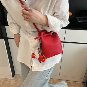 Detail der roten Eimertasche aus genarbtem Leder mit Elefantenanhänger und Kordelzugverschluss