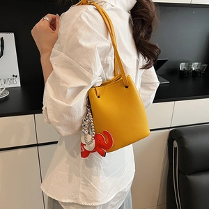 Detailansicht der gelben Bucket Bag aus Leder mit rotem Elefanten-Anhänger am Model