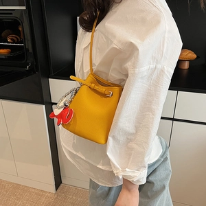 Detail der gelben Beuteltasche mit Litschi-Struktur und rotem Elefantenanhänger