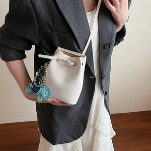 Detail der weißen Eimer-Tasche aus Leder mit einem bunten Elefanten-Anhänger