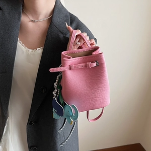 Details einer rosa Eimer-Tasche aus Leder mit Elefanten-Anhänger und Schultergurt