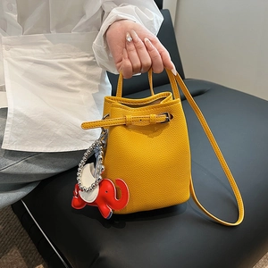 Detail der gelben Leder-Eimertasche mit Elefanten-Anhänger und Schulterriemen