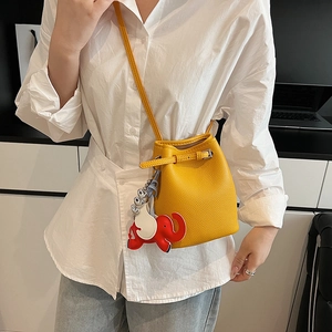 Gelbe Eimer-Tasche mit rotem Elefanten-Anhänger, getragen mit Jeans und weißem Hemd