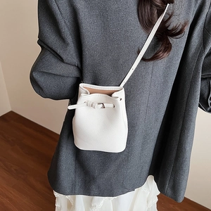 Detailansicht der weißen Mini-Beuteltasche aus Leder mit Lychee-Narbe und Schultergurt