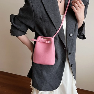 Detail einer rosa Mini-Beuteltasche aus Leder mit silberner Schnalle am grauen Anzug