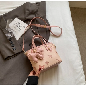 Detail of lychee pattern leather bucket bag with butterfly prints and dog charm decoration