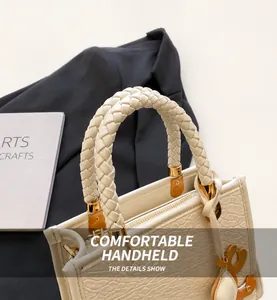 Détail du sac seau blanc cassé avec poignées tressées et surface en cuir texturé