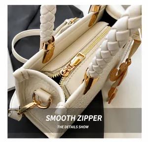 Détails de l'anse tressée, texture embossée et zip doré sur un sac seau blanc