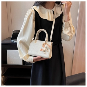 Détail du mini sac seau blanc texturé avec poignée tressée et breloque cheval