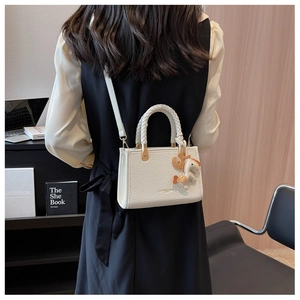 Détail du sac seau blanc texture crocodile avec poignée tressée et breloque cheval