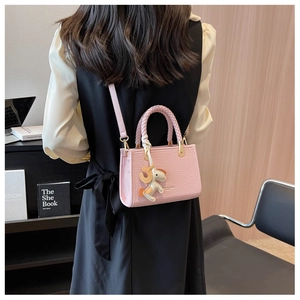 Détail du sac seau rose en similicuir avec poignée tressée et breloque petit poney