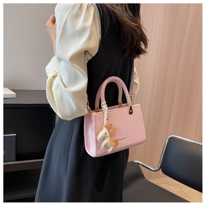 Vue détaillée du sac seau rose en cuir PU avec poignée tressée et breloque poney