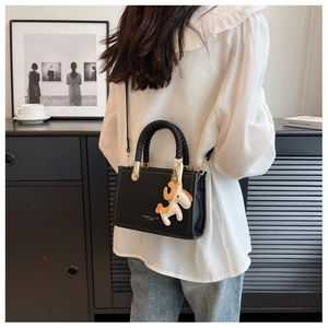 Détail du sac seau noir texturé avec poignée tissée et breloque cheval sur la sangle
