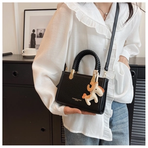 Détail du sac seau noir en simili cuir avec poignée tressée et breloque cheval décorative