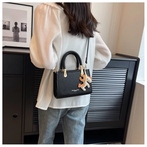 Détail du sac seau noir avec poignée tressée et breloque en cuir en forme de petit cheval