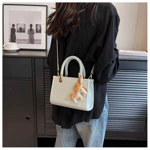 Détail du sac bandoulière en cuir vert menthe avec poignée tressée et breloque cheval