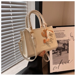 Détail du sac seau écru gaufré crocodile avec anses tressées et charm petit cheval