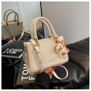 Détail du sac seau en cuir texturé blanc avec poignées tressées et breloque cheval
