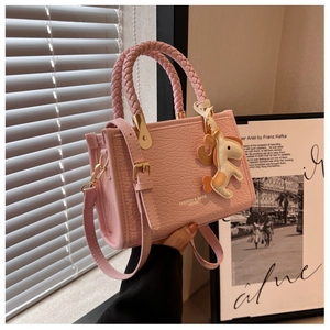 Détail du sac seau rose en cuir synthétique avec breloque cheval et anses tressées