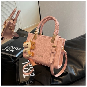 Vue détaillée du sac seau en cuir rose clair avec poignée tressée et charm de cheval