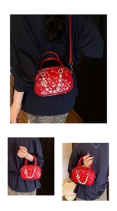 Macro shot of red quilted crossbody bag with pearl charms and luxury metal rivets