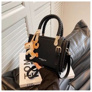 Détail du sac seau noir embossé croco avec poignée ronde tressée et breloque en forme de cheval