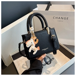 Gros plan d'un sac à main noir en cuir crocodile avec poignées tressées en coffret