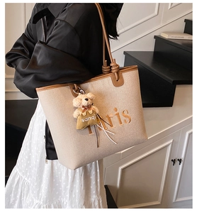 Detail of canvas tote bag with Paris embroidery and bear charm shown on model