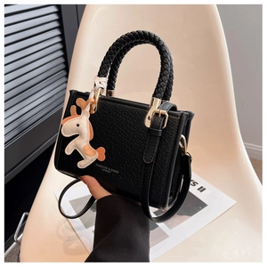 Détail du sac seau en cuir noir avec poignée en corde et breloque poney orange