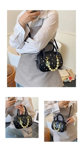 Detail of quilted black handbag with pearl chain handle and butterfly charm