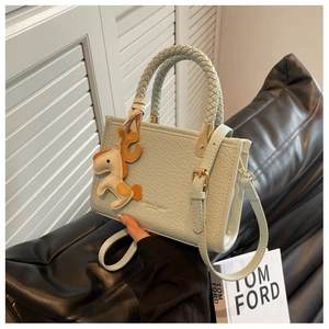 Gros plan du mini sac seau bleu clair effet croco avec poignée tressée et breloque