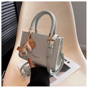 Détail du sac à bandoulière en cuir vert menthe avec poignée tressée et breloque cheval