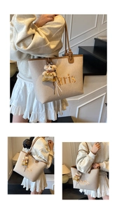 Detail of beige canvas tote bag with Paris embroidery and brown leather handle