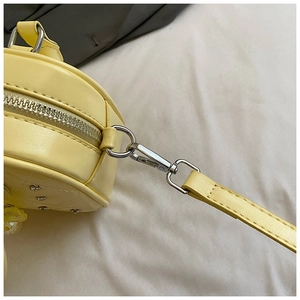 Detail shot of a yellow mini bowling bag showing metal zipper and rhinestone accents