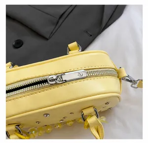 Macro detail of silver zipper and quilting on a pale yellow PU leather bowling bag