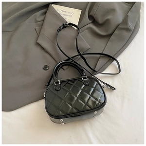 Close-up of quilted black patent leather handbag with silver studs and chain strap