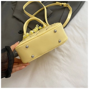 Detail view of the yellow leather bowling bag with silver feet and quilted stitching