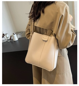 Détail du sac seau en cuir crème montrant la couture verticale et le logo embossé