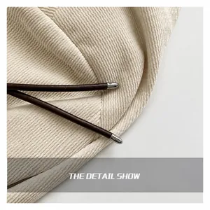 Detailed macro of cream corduroy fabric with dark brown drawstring and silver hardware