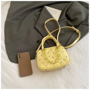Macro shot of yellow quilted mini bowling bag with rhinestones and beaded chain detail