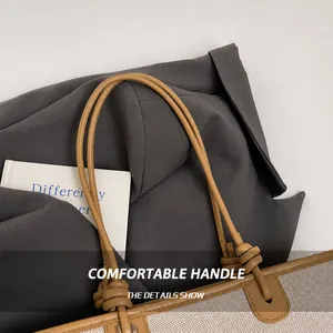 Close-up of the brown leather knotted handle and beige canvas texture of the tote bag
