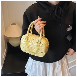Detail of yellow quilted Boston bag with rhinestones and beaded handle decoration