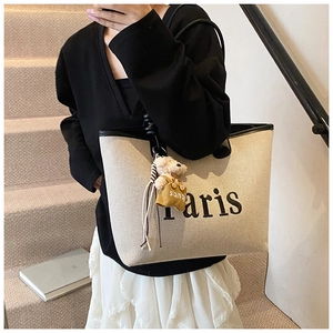 Detailed shot of white canvas tote bag with Paris print and cute bear charm on stairs