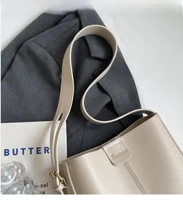 Vue détaillée du sac seau en cuir crème avec logo gaufré et fermeture magnétique